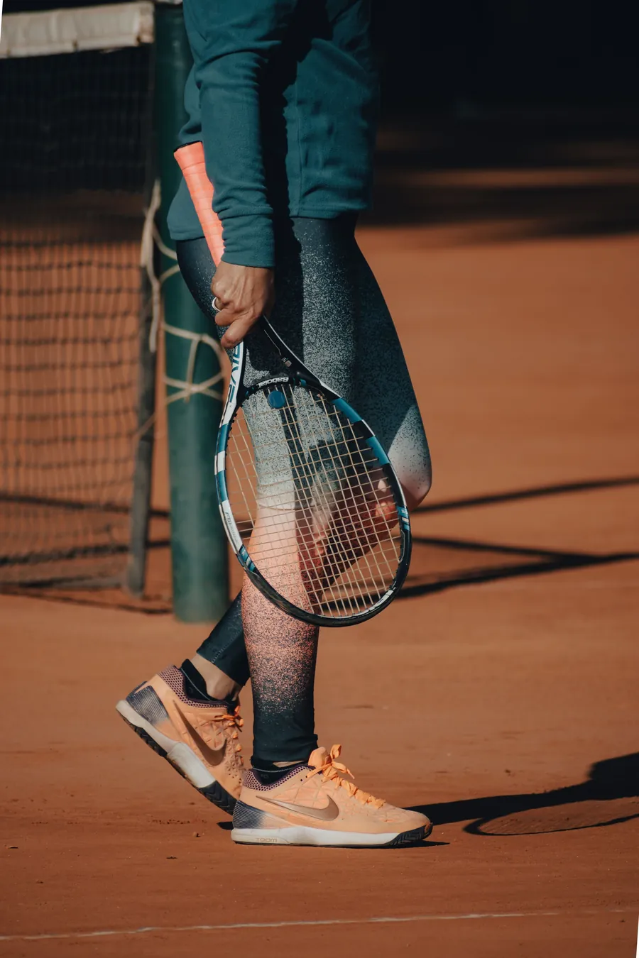 Player carrying a Babolat tennis racket on a clay court