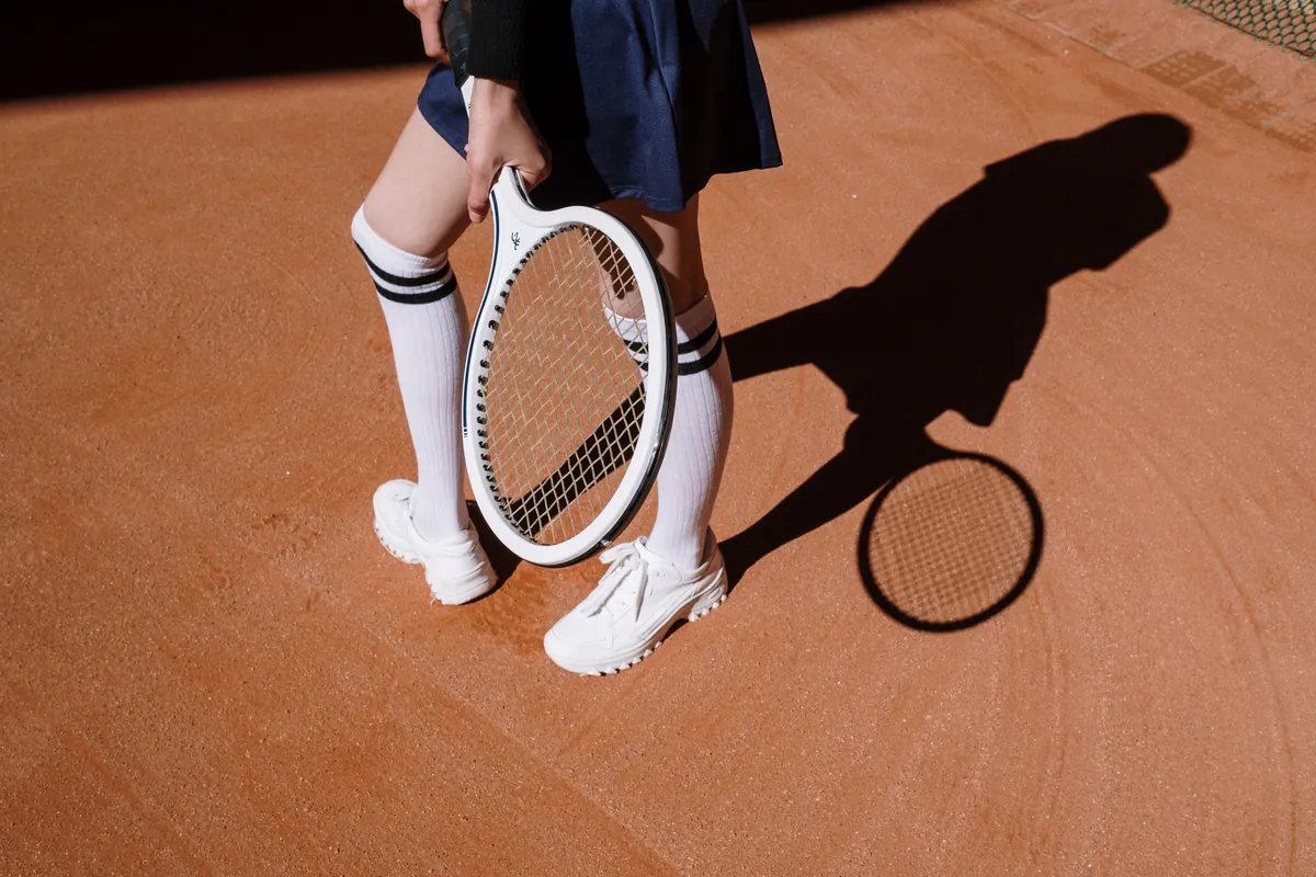 Close view of a strung tennis racket held over a clay court
