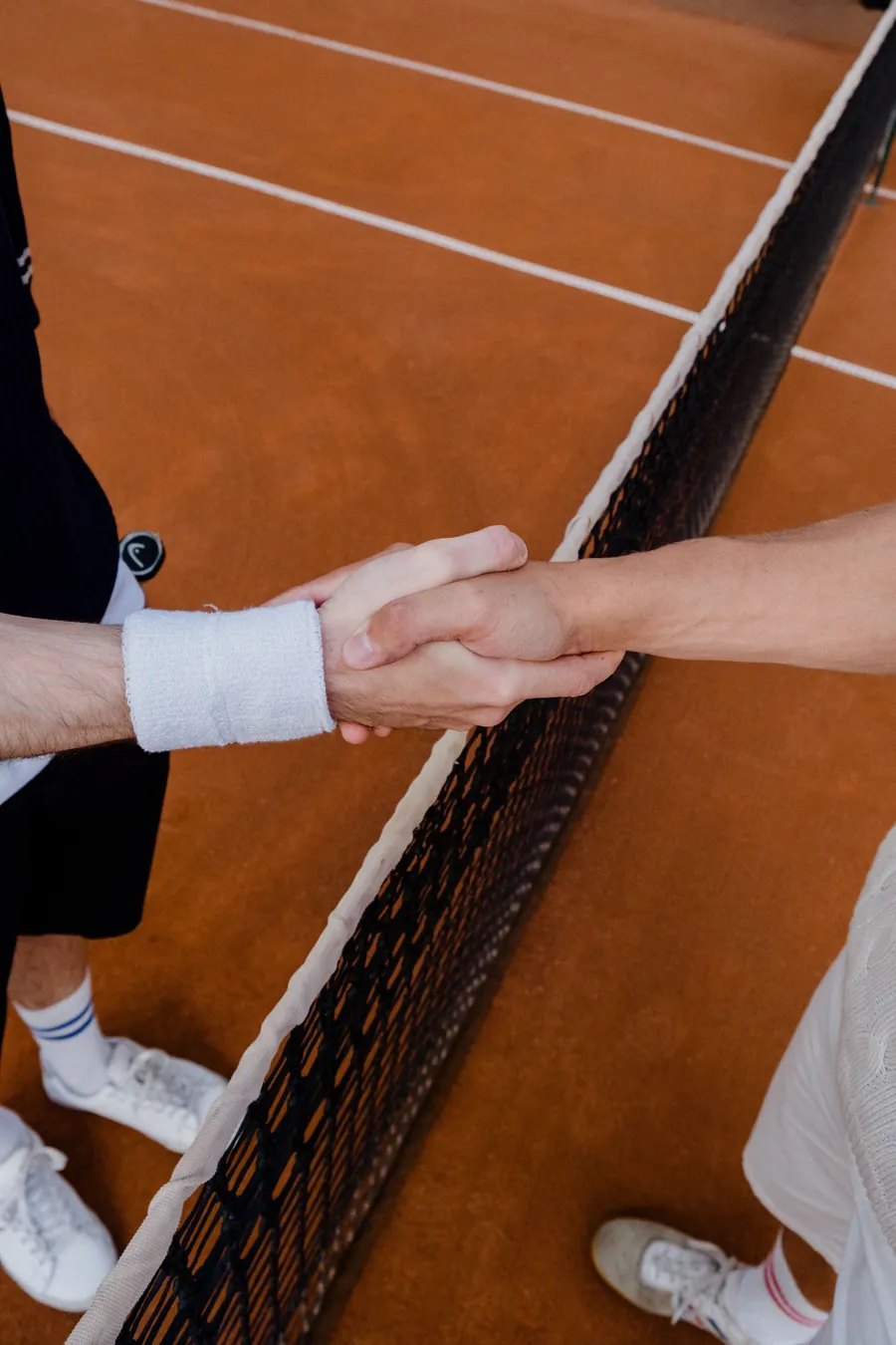 Two tennis players shaking hands over the net after a match